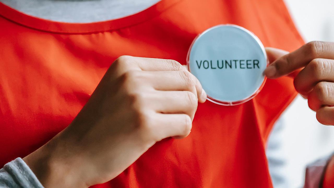 volunteer wearing a red shirt with badge saying volunteer